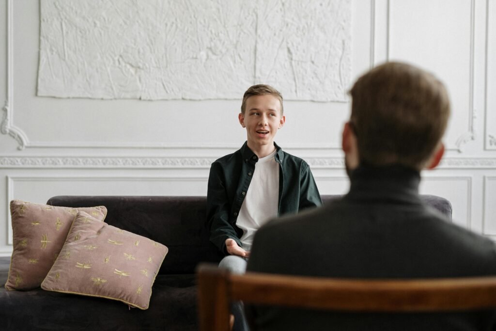 A young man engages in a therapy session with a counselor in a modern office setting.